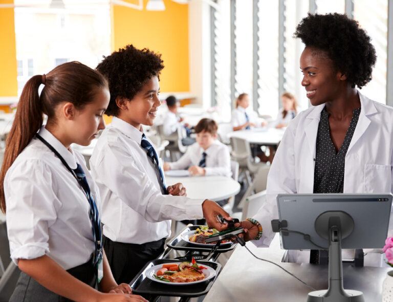 School worker in front of NE150 tablet stand with two students in uniform