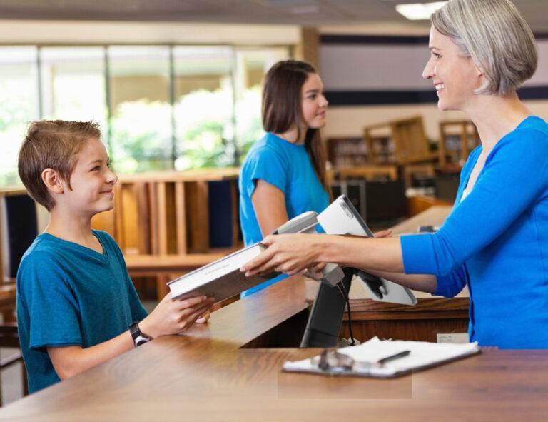 Teacher handing secure tablet to young student