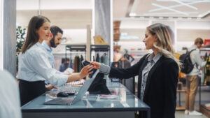 Retail associate processing a customer return at the point of sale counter, illustrating the importance of return verification procedures to prevent fraudulent returns and inventory loss.