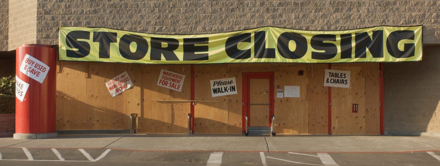 Image of large store with sign out front announcing "store closing"
