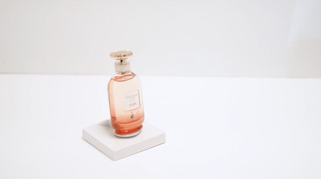 Fragrance tester mounted on InVue Tile, a low-profile square tester display, on a white surface