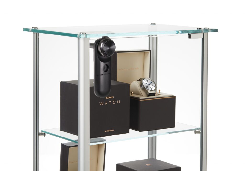 InVue LIVE Cam Lock mounted on a glass showcase securing boxed smartwatches on display shelves