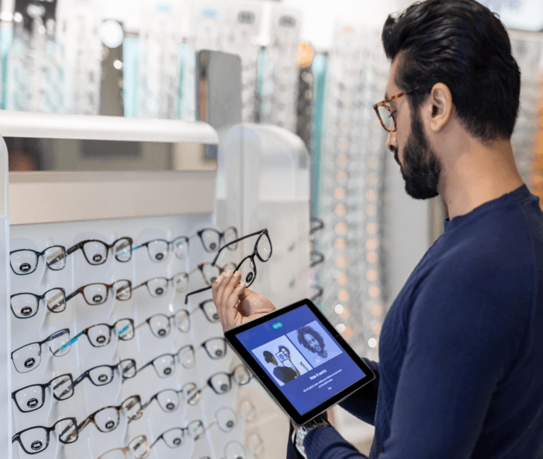 Man holding eyeglasses while holding a handheld tablet
