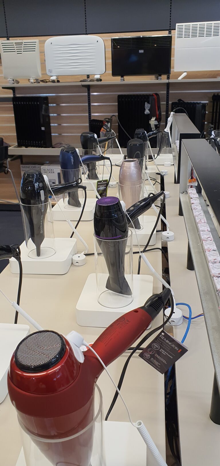 Hairdryers being secured and tethered to display fixtures to prevent theft and organized retail crime.