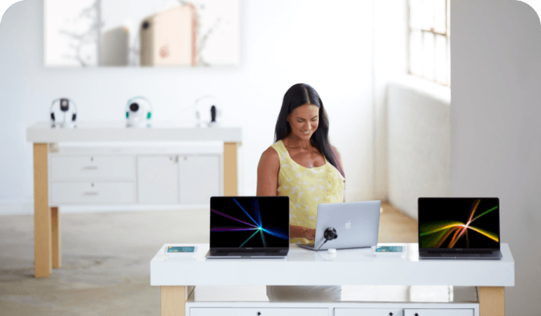 Woman looking at laptops on a table in a mobile carrier store