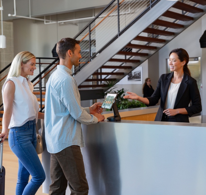 Two women and a man with a NE150 Convertible POS Stand