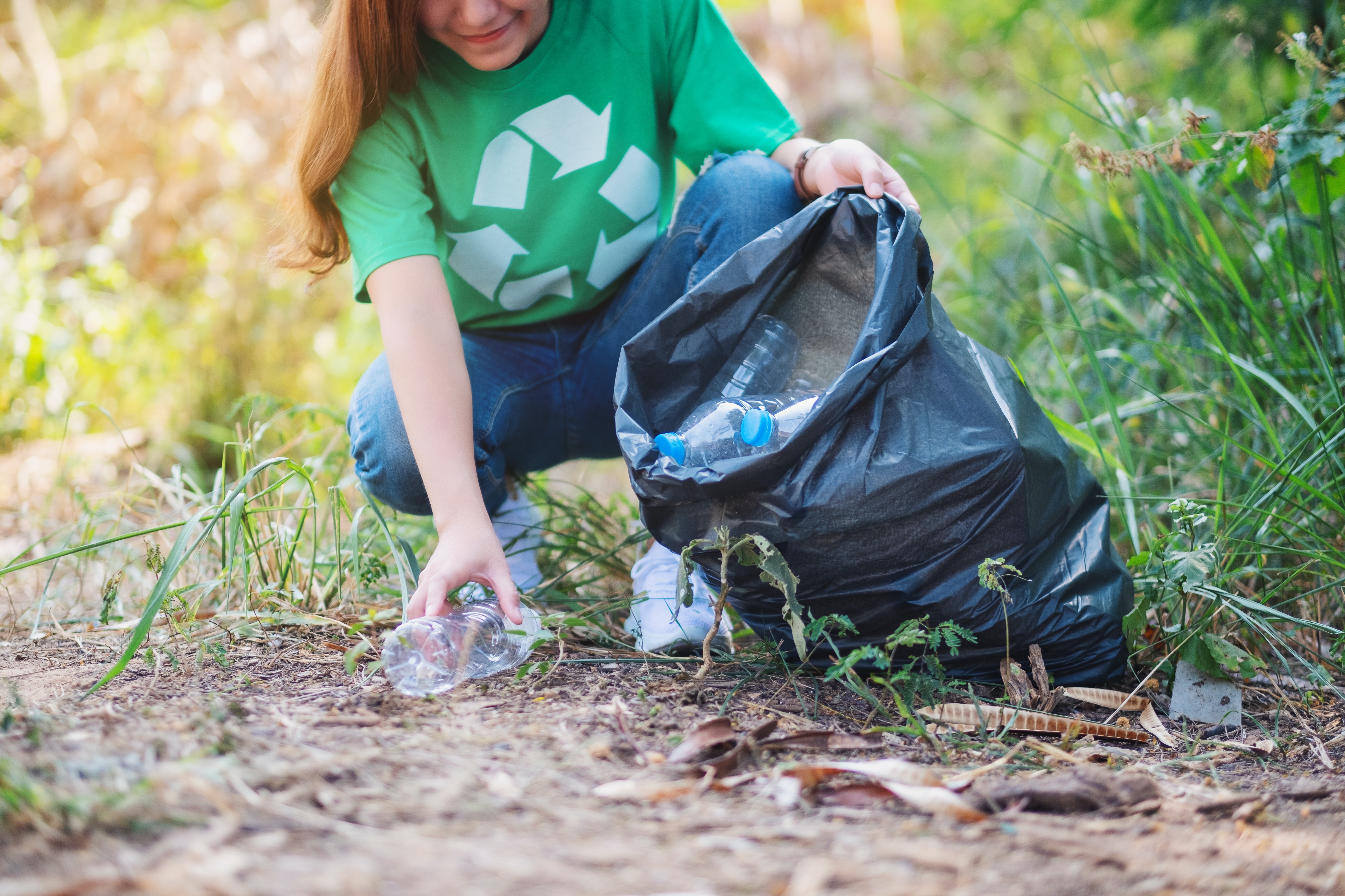 Woman picking up recycling and putting it in the trash