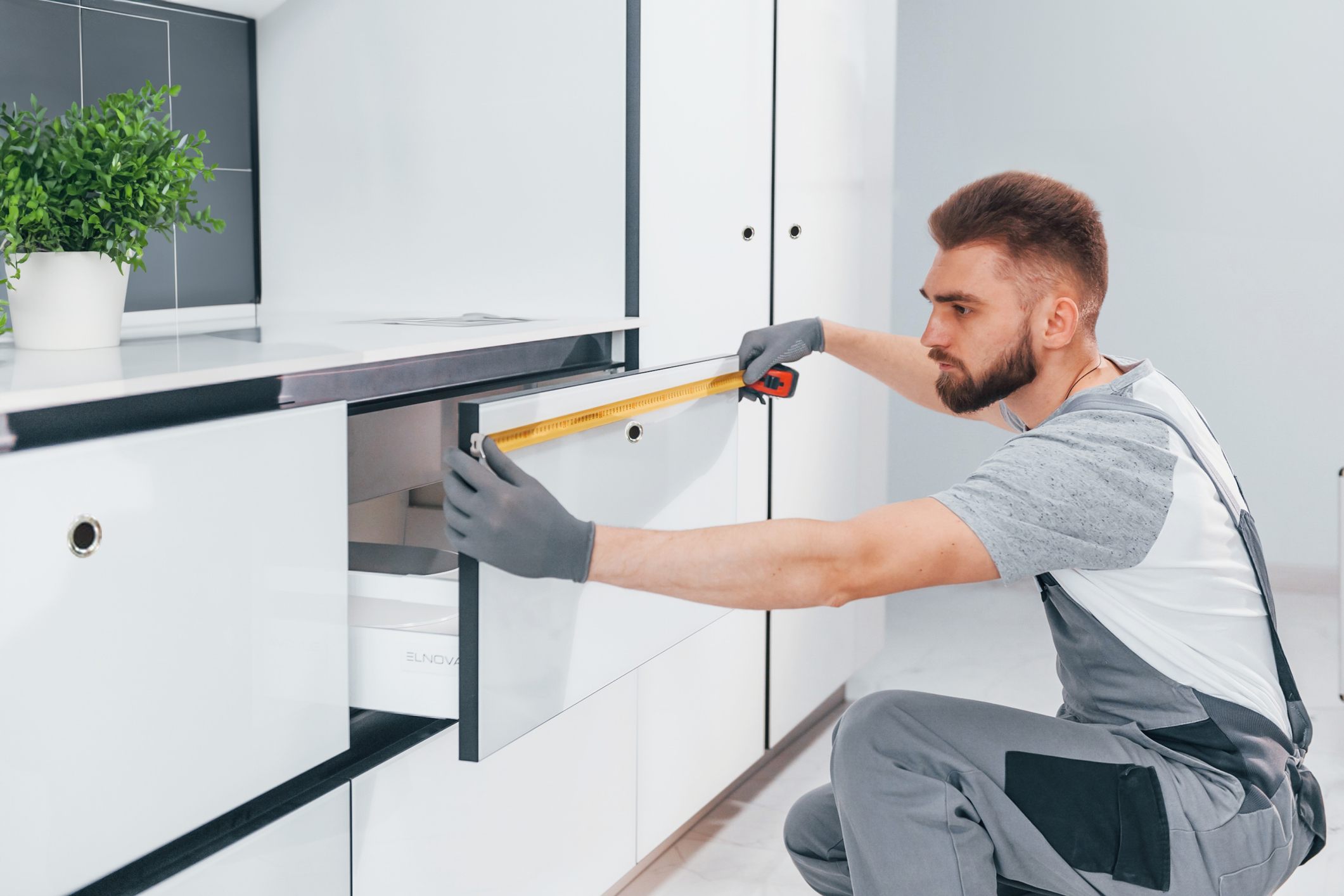 Man measuring a white drawer with a lock